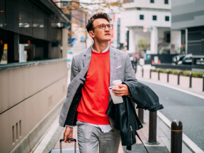 Business casual youn male walking downtown carrying jacket and coffee
